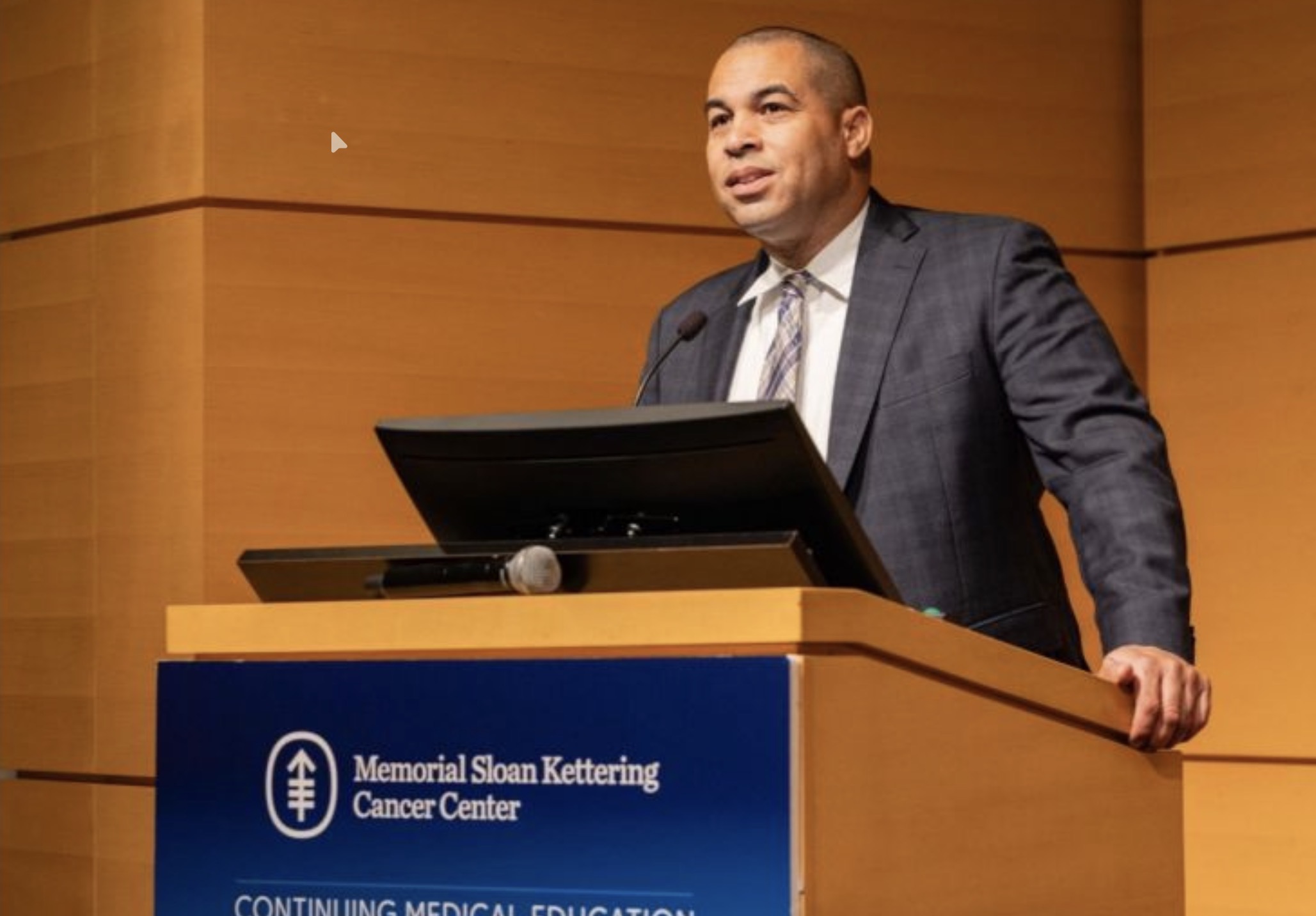 A speaker presenting at a medical education lectern