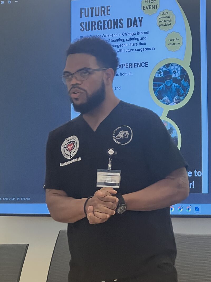 A presenter speaking beside a Future Surgeons Day display